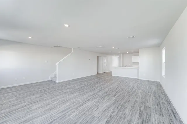 a view of an empty room with wooden floor and window