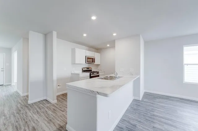 a kitchen with a sink a stove cabinets and wooden floor