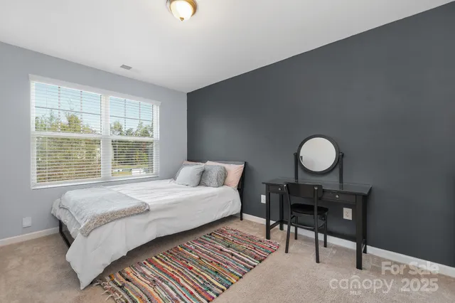 a bedroom with a bed a desk and chair with the wooden floor