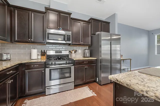 a kitchen with granite countertop wooden cabinets stainless steel appliances and a counter space