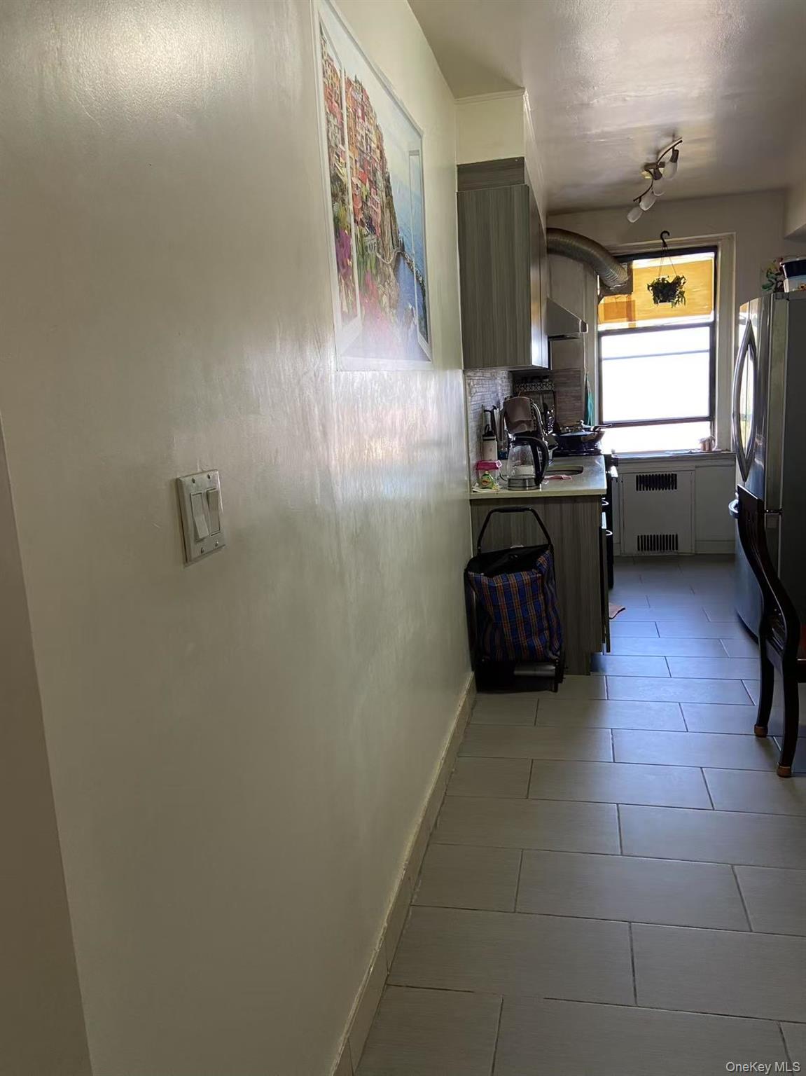 40-35 Ithaca Street, Unit 5B Queens, NY 11373 - Photo 5 of 10 Kitchen with light countertops, light tile patterned floors, freestanding refrigerator, and radiator heating unit
