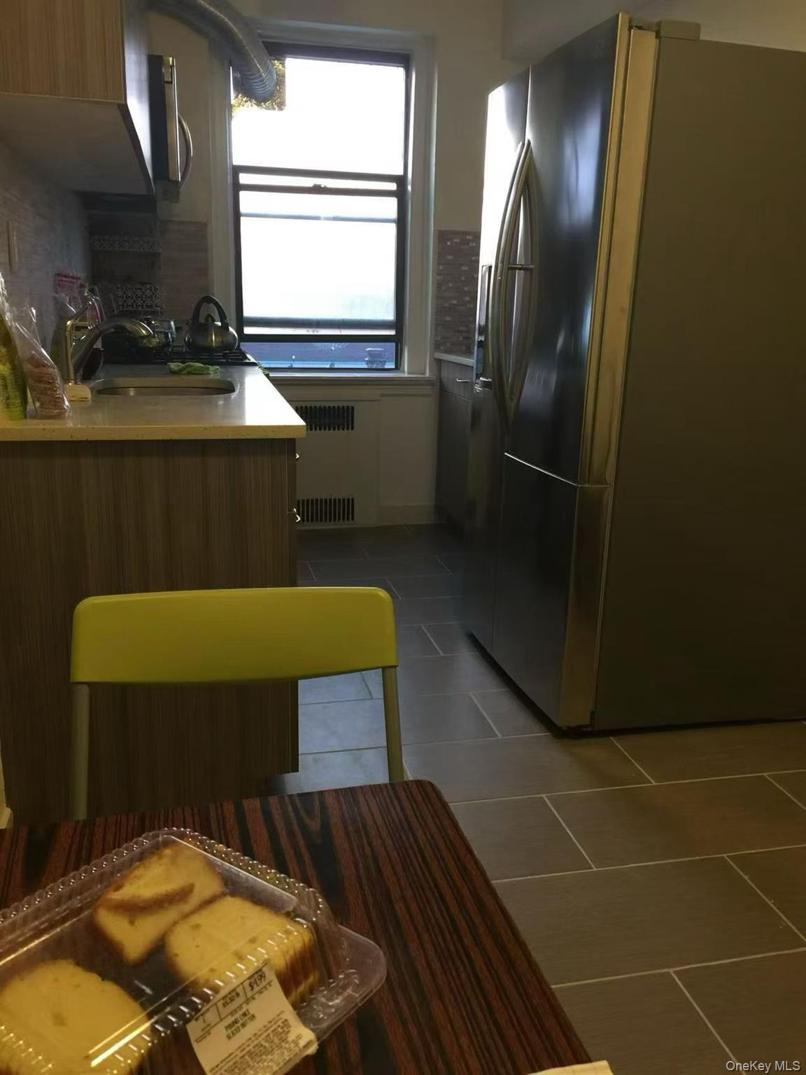 40-35 Ithaca Street, Unit 5B Queens, NY 11373 - Photo 6 of 10 Kitchen with appliances with stainless steel finishes, light countertops, light tile patterned flooring, and radiator