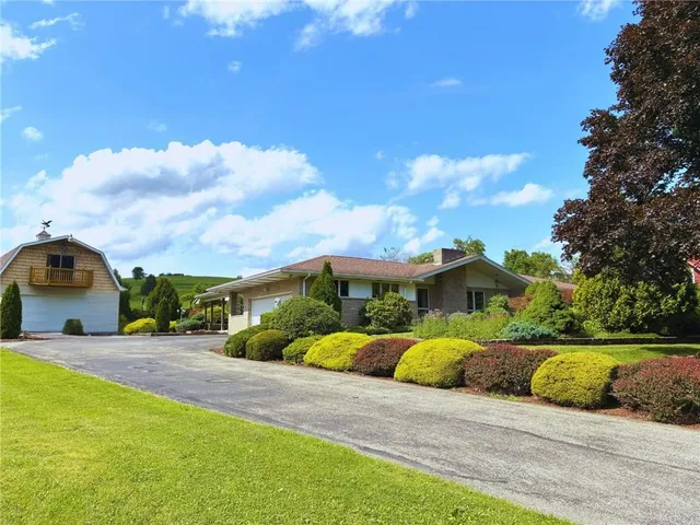 a view of a house with a big yard and large trees