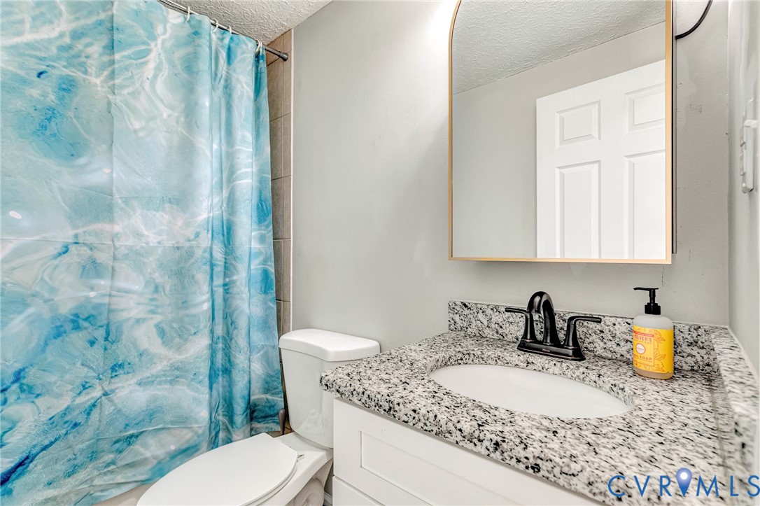 16004 Gary Avenue Chester, VA 23831 - Photo 21 of 26 a bathroom with a granite countertop sink a mirror a toilet and shower curtain