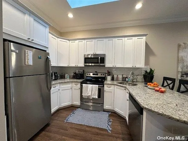 a kitchen with granite countertop a refrigerator stove top oven a sink and dishwasher