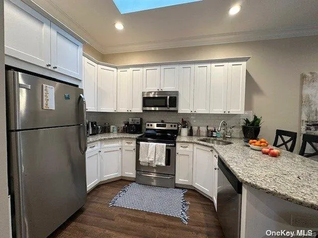 a kitchen with granite countertop a refrigerator stove top oven a sink and dishwasher