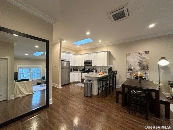 a kitchen with stainless steel appliances kitchen island granite countertop a table chairs in it and a living room view