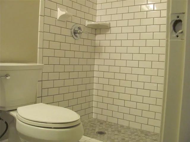 a white toilet sitting next to a white wall