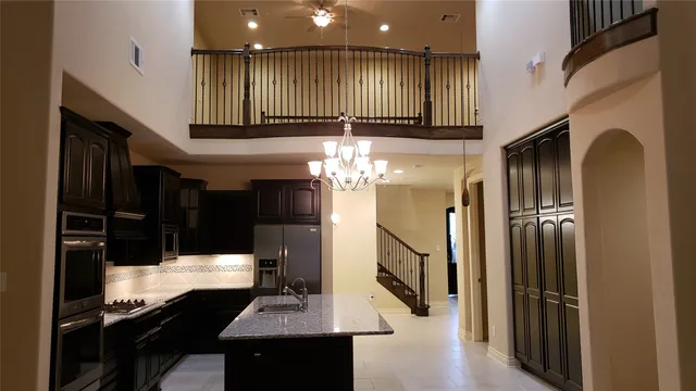 a kitchen with stainless steel appliances kitchen island granite countertop a refrigerator a stove and a sink with wooden floor