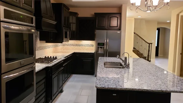 a kitchen with stainless steel appliances granite countertop a sink and a refrigerator