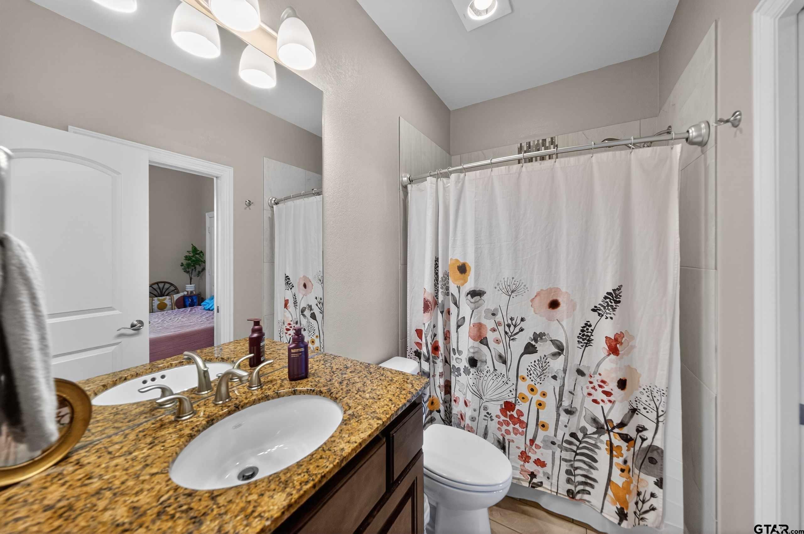 2202 Rana Park Flint, TX 75762 - Photo 34 of 47 a bathroom with a granite countertop toilet a sink a mirror a lamp and shower curtain