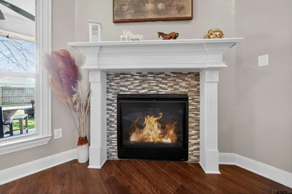 a view of an empty room with wooden floor and a fireplace