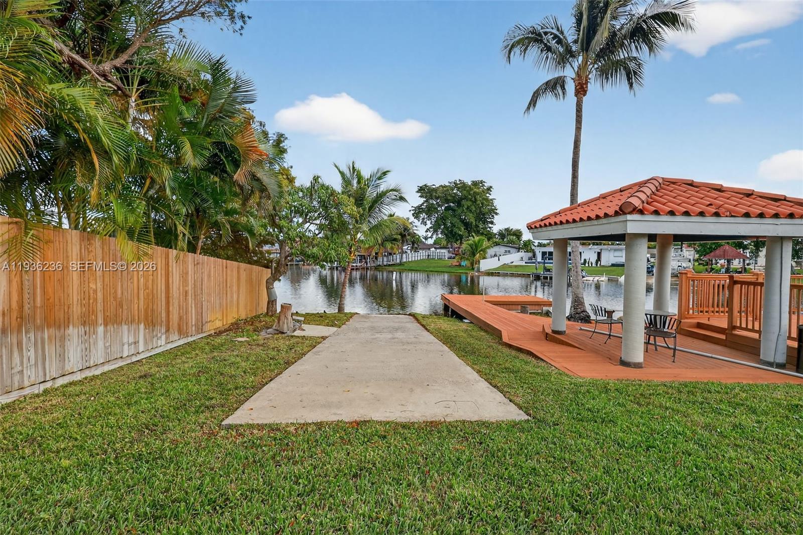17841 Northwest 84th Court Hialeah, FL 33015 - Photo 52 of 76 a view of a patio with table and chairs under an umbrella with wooden fence