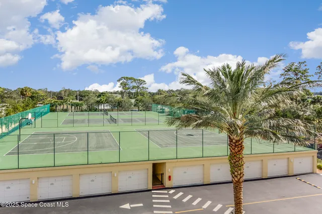a view of a tennis ground with large trees