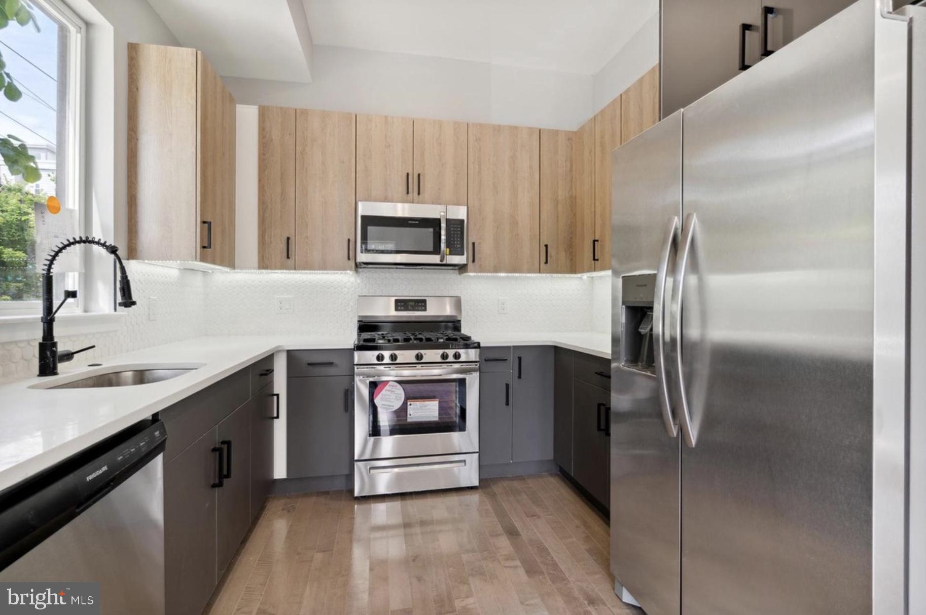 2000 North 3rd Street, Unit 1 Philadelphia, PA 19122 - Photo 3 of 10 a kitchen with kitchen island stainless steel appliances a sink stove refrigerator and a window