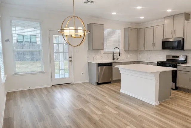 a kitchen with stainless steel appliances granite countertop a stove a sink dishwasher and a white countertops with wooden floor