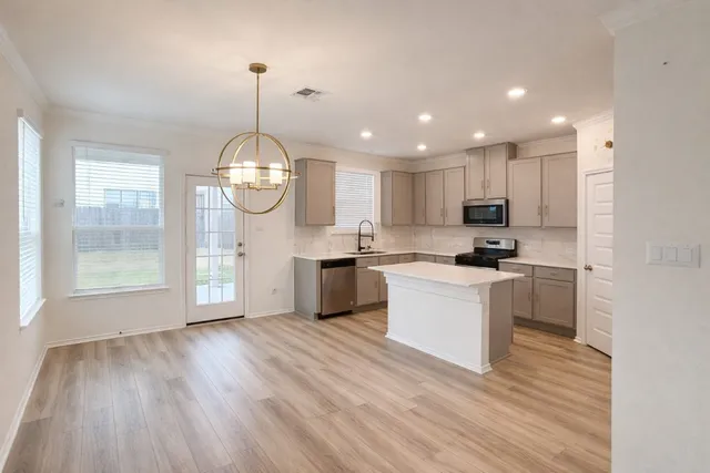 a kitchen with cabinets wooden floor and stainless steel appliances