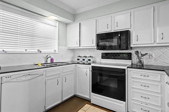 a kitchen with stainless steel appliances a sink dishwasher a stove and white cabinets