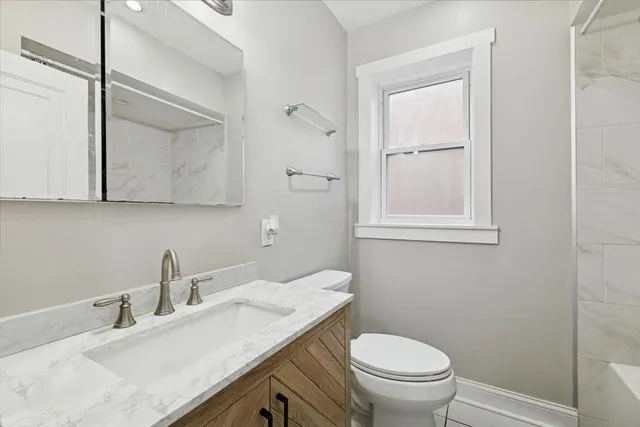 a bathroom with a granite countertop sink a toilet and a mirror