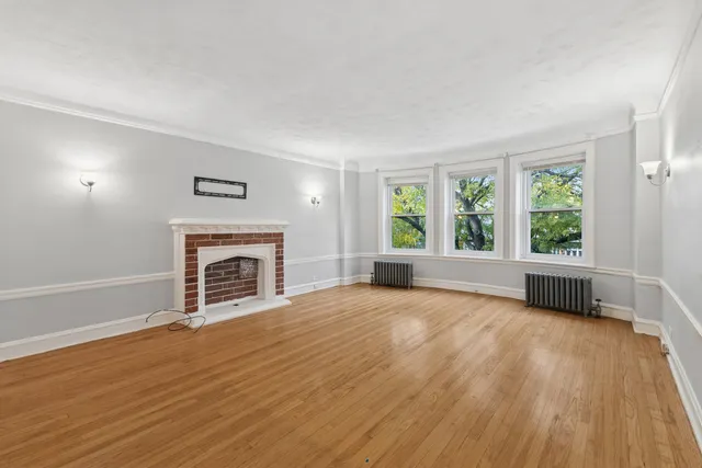 wooden floor fireplace and windows in an empty room