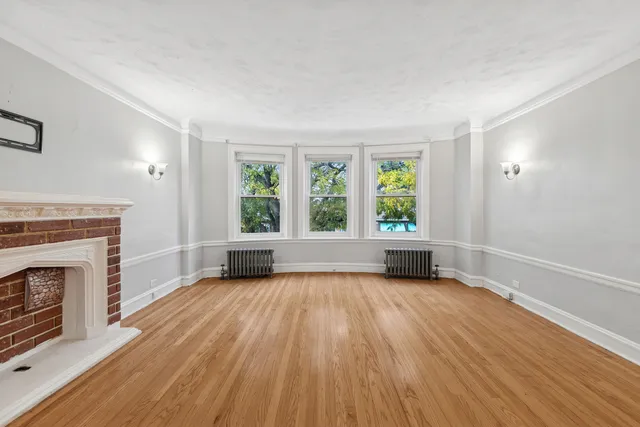 an empty room with large windows and fireplace