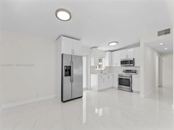 a kitchen with white cabinets and stainless steel appliances
