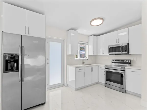 a kitchen with stainless steel appliances granite countertop a refrigerator a stove a sink and a microwave