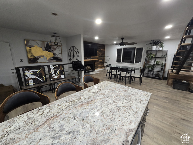 1397 Ritter Drive Riverdale, UT 84405 - Photo 4 of 21 Integrated living space featuring wood-finish flooring, a built-in fireplace with wood accent wall, a dining area, and a kitchen island with a stone countertop