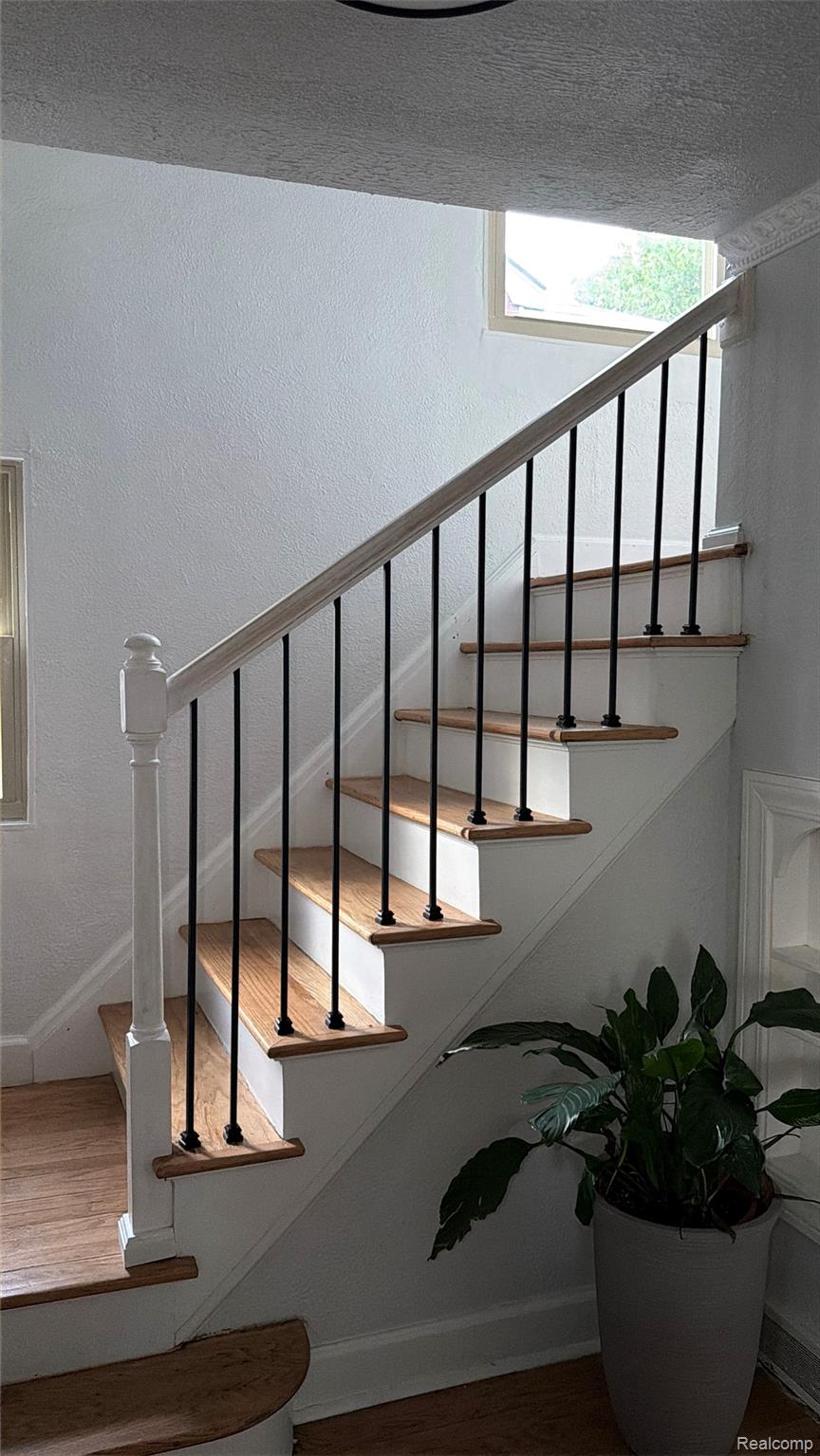 3914 Balfour Road Detroit, MI 48224 - Photo 19 of 24 Staircase featuring wood-finish treads, painted risers, and a white newel post