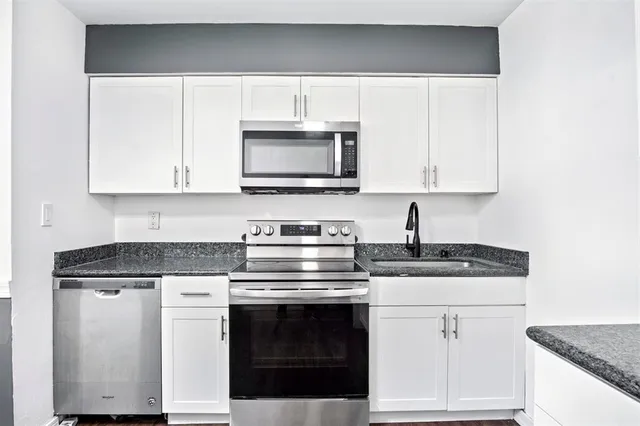 a kitchen with granite countertop a stove top oven microwave and cabinets