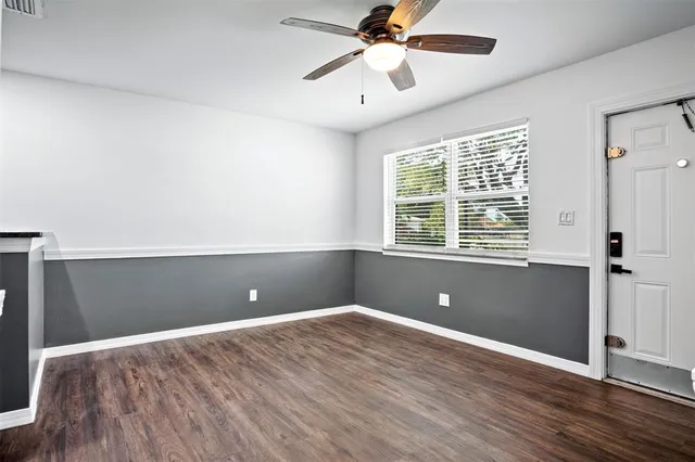 a view of empty room with wooden floor and fan