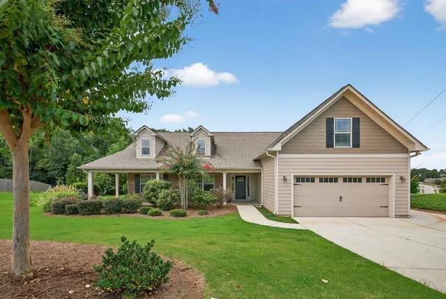 a view of a house with a yard potted plants and a table