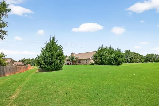 a view of a green yard with a house in the background