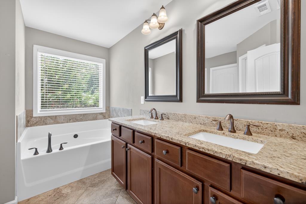 445 Katherine Drive Jefferson, GA 30549 - Photo 22 of 41 a bathroom with double vanity sinks a large mirror and a bathtub