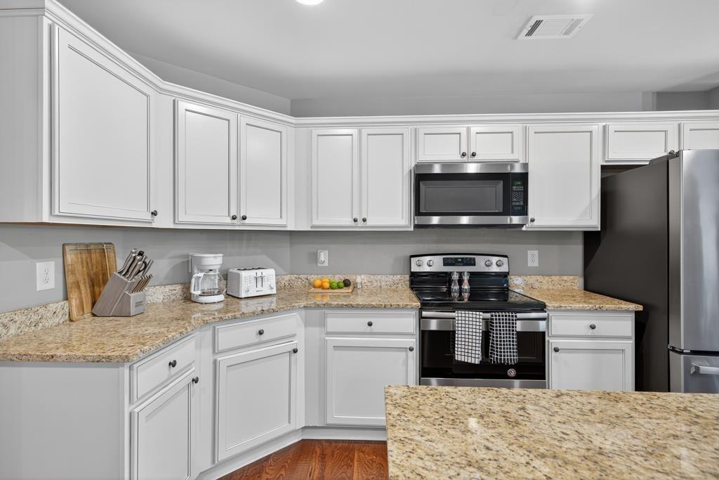 445 Katherine Drive Jefferson, GA 30549 - Photo 35 of 41 a kitchen with stainless steel appliances granite countertop a stove top oven a refrigerator a sink and dishwasher with white cabinets