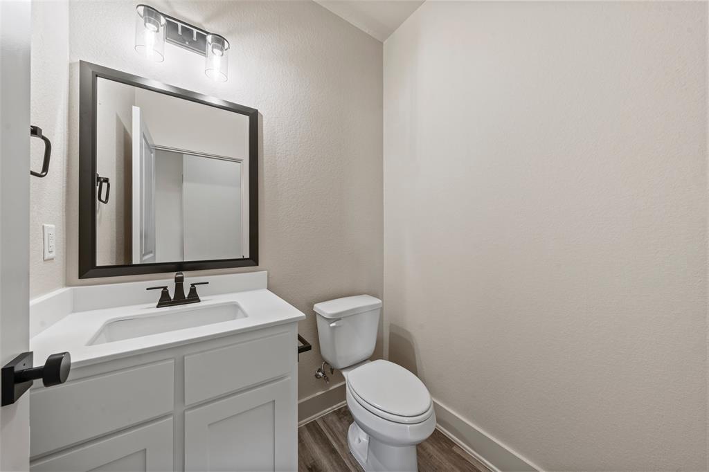 138 Dana Pt Road Lorena, TX 76655 - Photo 19 of 24 Bathroom featuring a white vanity with an integrated sink, dark bronze hardware, a framed mirror, and wood-finish flooring