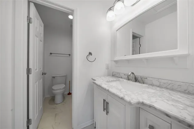 a bathroom with a granite countertop sink a toilet and a mirror