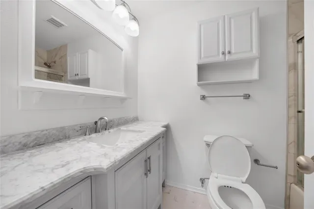 a bathroom with a granite countertop toilet sink and mirror