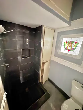 a bathroom with a granite countertop toilet a sink and a window