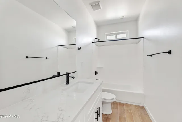 a bathroom with a sink a toilet a vanity and shower