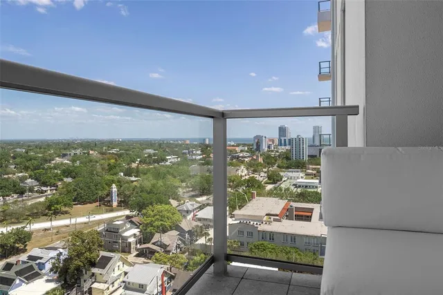 a large living room with stainless steel appliances kitchen island granite countertop a large window and a wooden floor
