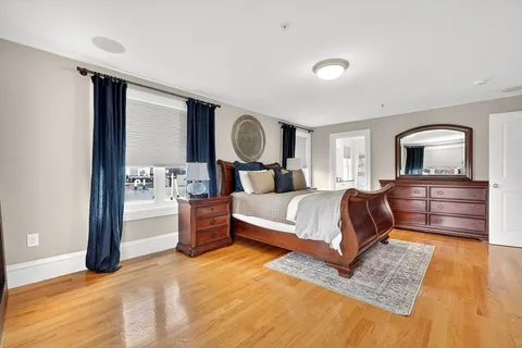 a bedroom with a bed wooden floor and window