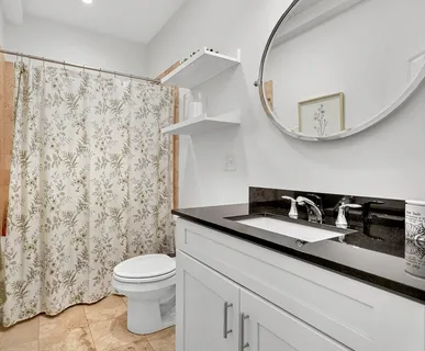 a bathroom with a granite countertop sink a toilet and a mirror