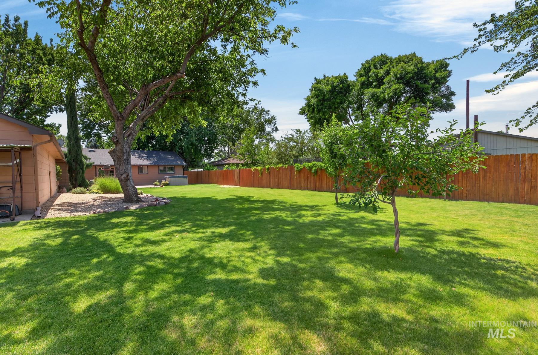 9622 Delaware Street Boise, ID 83709 - Photo 42 of 48 Expansive green lawn featuring mature trees and a privacy fence