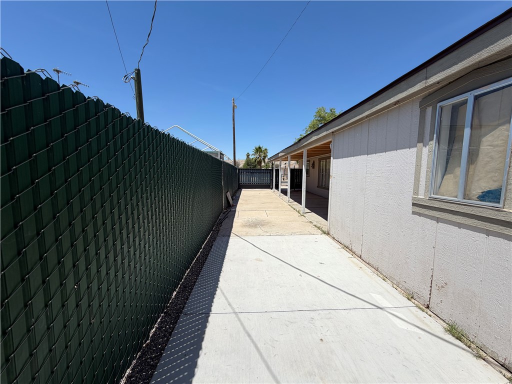 1910 Rio Grande Road Bullhead City, AZ 86442 - Photo 29 of 29 Side yard featuring a concrete pathway, green chain-link fencing, and a covered porch area