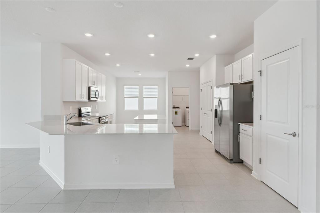 1672 Rider Rain Lane Apopka, FL 32703 - Photo 13 of 35 a large white kitchen with a refrigerator a sink and a stove
