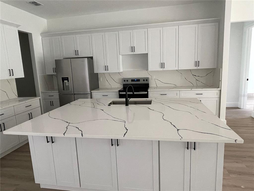 41719 Aspen Street Eustis, FL 32736 - Photo 16 of 52 a kitchen with a refrigerator a stove a sink and white cabinets