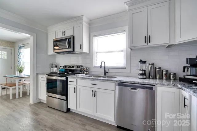 a kitchen with cabinets appliances a sink and a window