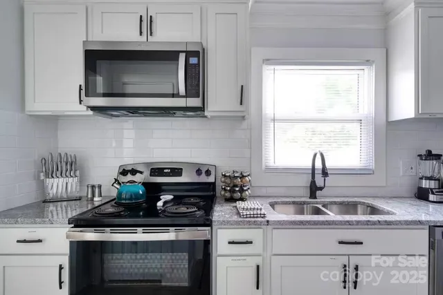 a kitchen with stainless steel appliances granite countertop a sink a stove a microwave a counter space and cabinets