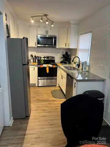 a kitchen with stainless steel appliances granite countertop a refrigerator a stove a sink and a microwave